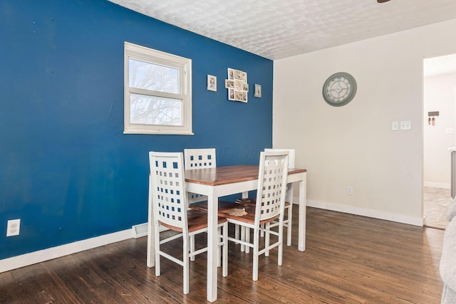 dining room featuring dark wood-type flooring and a textured ceiling