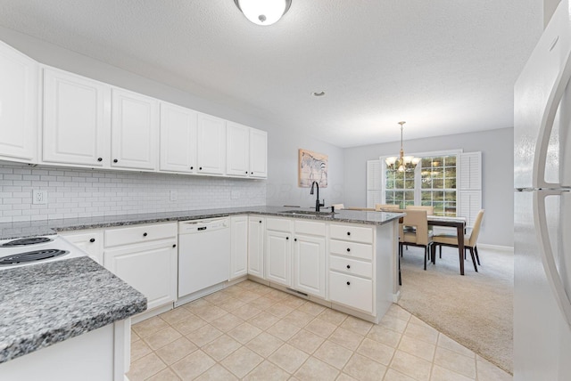 kitchen with kitchen peninsula, hanging light fixtures, sink, white appliances, and white cabinets