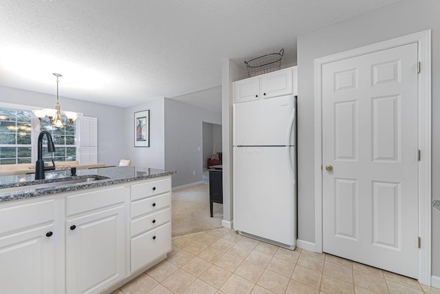 kitchen with decorative light fixtures, white refrigerator, sink, a textured ceiling, and white cabinets