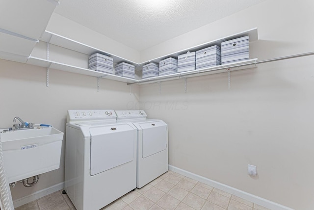 washroom with light tile patterned flooring, independent washer and dryer, sink, and a textured ceiling