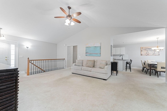 living room with sink, high vaulted ceiling, light colored carpet, and ceiling fan with notable chandelier