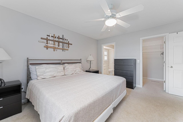 carpeted bedroom featuring ceiling fan, a closet, ensuite bath, and a spacious closet