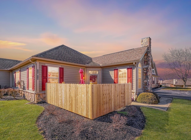 property exterior at dusk featuring a lawn