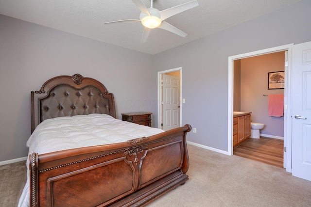 bedroom featuring light carpet, ensuite bathroom, and ceiling fan