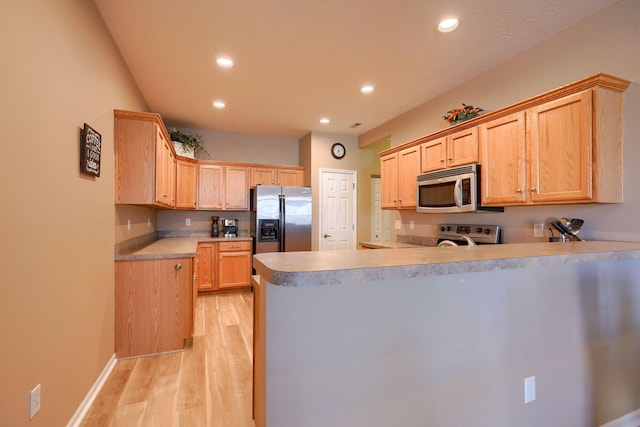 kitchen featuring kitchen peninsula, light brown cabinets, stainless steel appliances, and light hardwood / wood-style floors