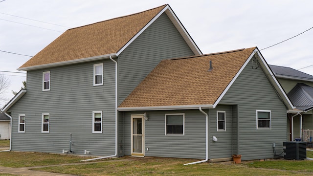 rear view of property with cooling unit and a yard