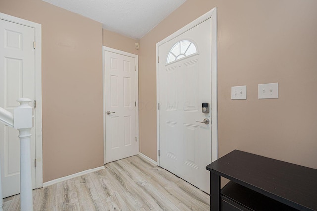 entryway with a textured ceiling and light hardwood / wood-style flooring