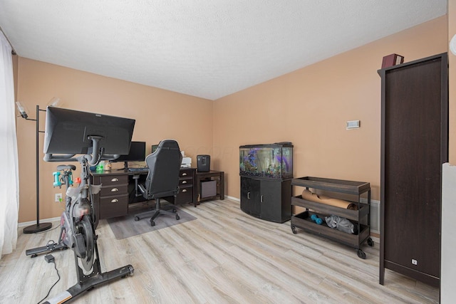 home office featuring light wood-type flooring and a textured ceiling