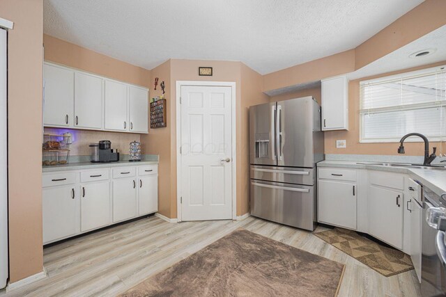 kitchen with white cabinetry, sink, light hardwood / wood-style floors, and stainless steel refrigerator with ice dispenser