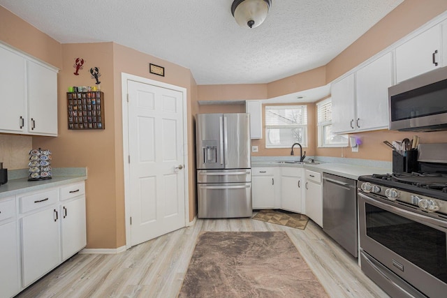 kitchen featuring sink, stainless steel appliances, white cabinetry, and light hardwood / wood-style floors