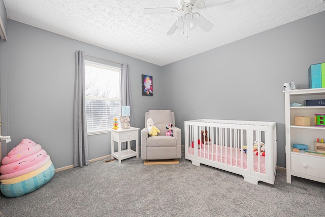 carpeted bedroom with a crib, a textured ceiling, and ceiling fan