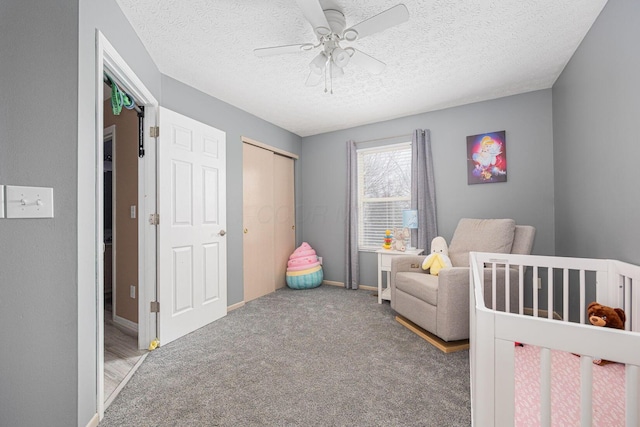 bedroom with a closet, a textured ceiling, ceiling fan, carpet floors, and a nursery area