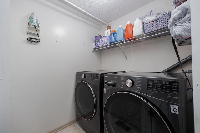 washroom with a textured ceiling, light tile patterned flooring, and washing machine and clothes dryer