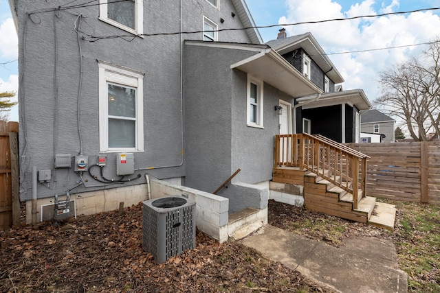 view of property exterior featuring stucco siding, fence, and central air condition unit