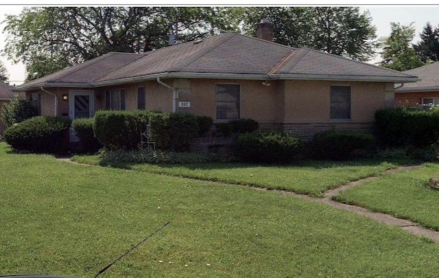 ranch-style house featuring brick siding, a chimney, and a front yard