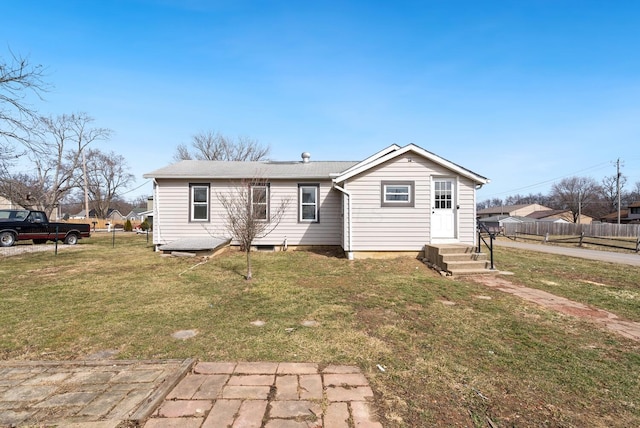 rear view of property featuring fence, a lawn, and entry steps