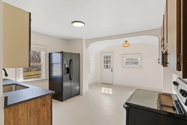 2029 Fairfax Ave, Columbus, OH 43207 - kitchen with dark countertops, black fridge, arched walkways, electric range, and a sink