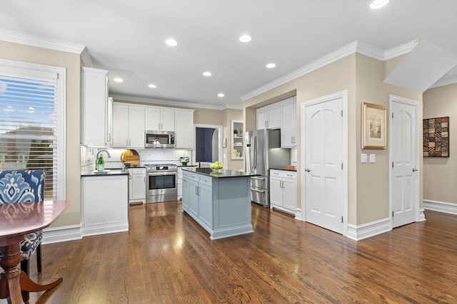 kitchen with white cabinets, dark countertops, dark wood-style floors, a kitchen island, and stainless steel appliances