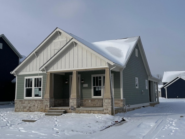 view of front of property with covered porch, stone siding, and board and batten siding