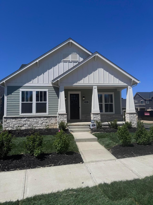 view of front facade featuring board and batten siding, a porch, and stone siding