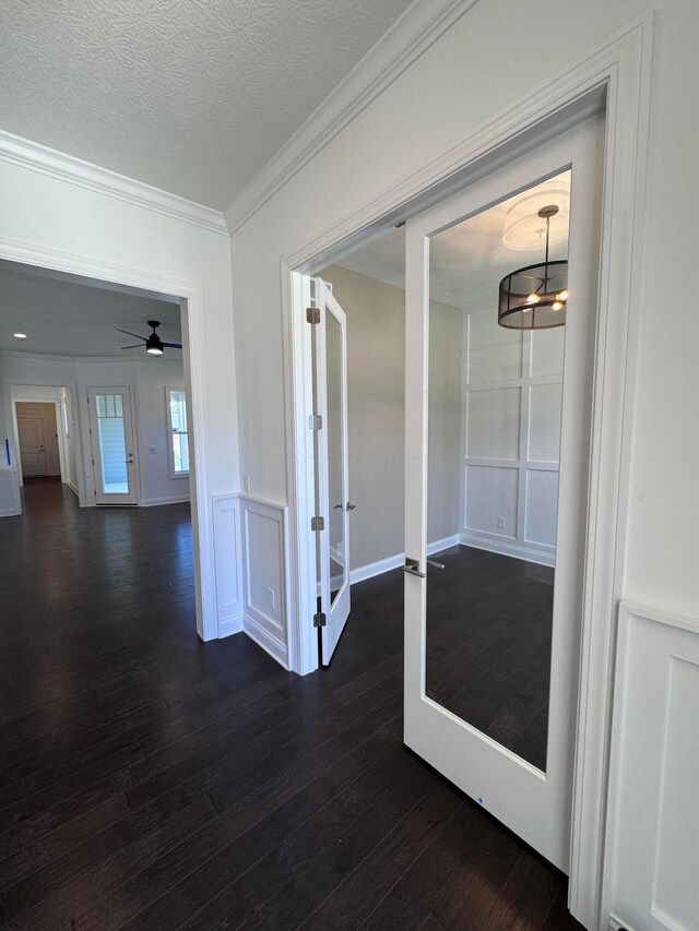 corridor featuring dark wood-style flooring, french doors, crown molding, and a textured ceiling