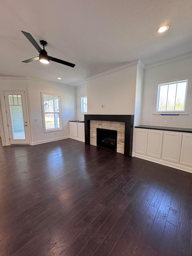 unfurnished living room with dark wood-style floors, recessed lighting, ornamental molding, a fireplace, and a ceiling fan