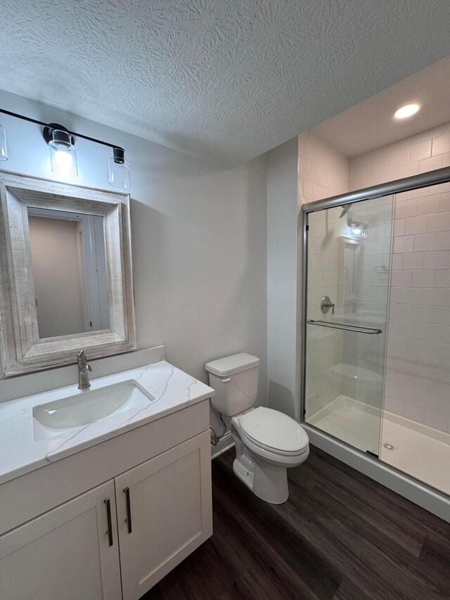 5450 Maple Dr, Lewis Center, OH 43035 - bathroom with wood finished floors, a textured ceiling, toilet, and a stall shower