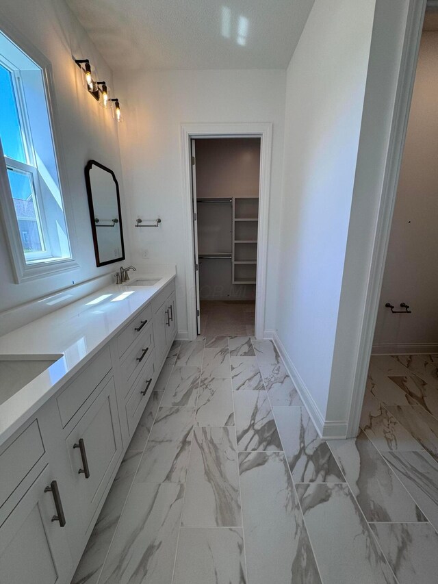 5450 Maple Dr, Lewis Center, OH 43035 - bathroom with double vanity, marble finish floor, a sink, baseboards, and a spacious closet