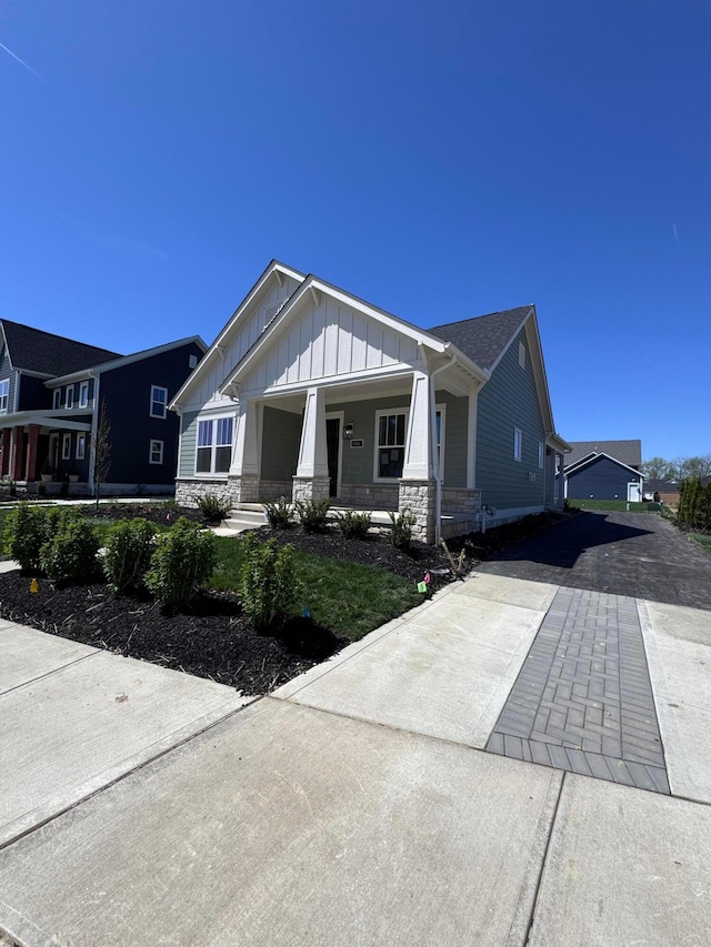 5450 Maple Dr, Lewis Center, OH 43035 - craftsman house featuring board and batten siding, a porch, driveway, and stone siding