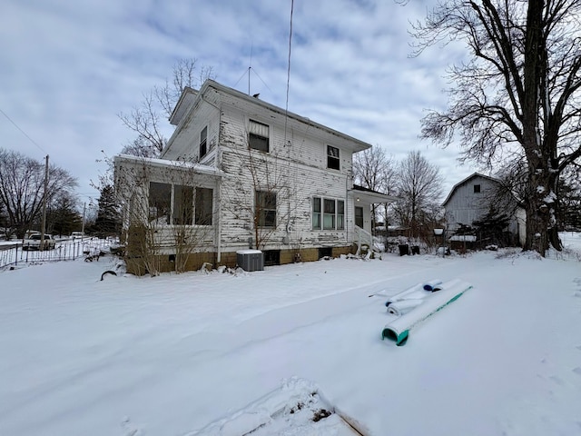 snow covered rear of property featuring central AC