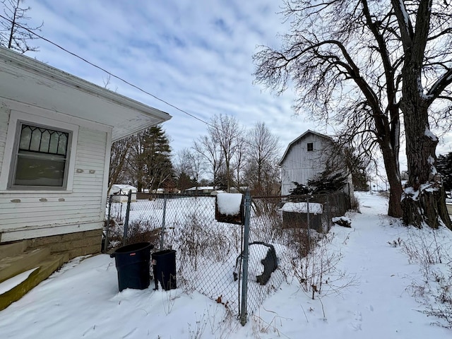 yard covered in snow with an outdoor structure, fence, and a barn