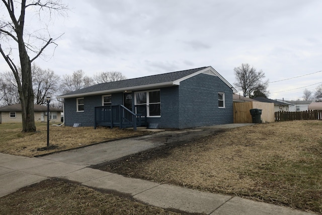 single story home featuring brick siding, fence, and roof with shingles