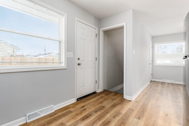 foyer entrance with baseboards, visible vents, and light wood-style flooring