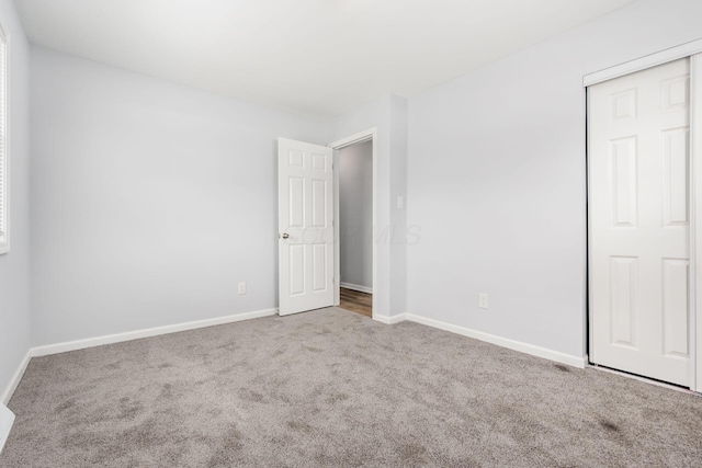 unfurnished bedroom featuring a closet, carpet flooring, and baseboards