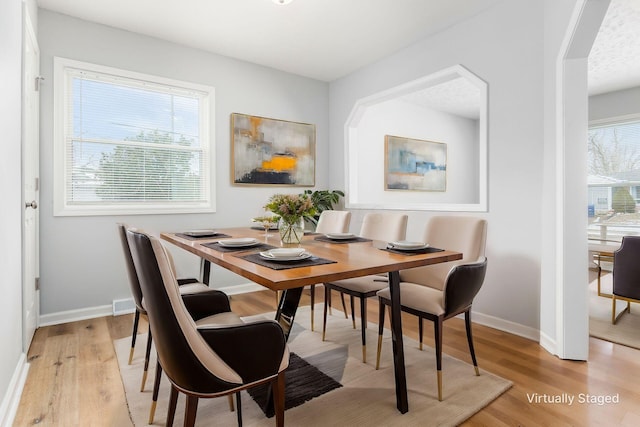 dining space with light wood finished floors, visible vents, and baseboards