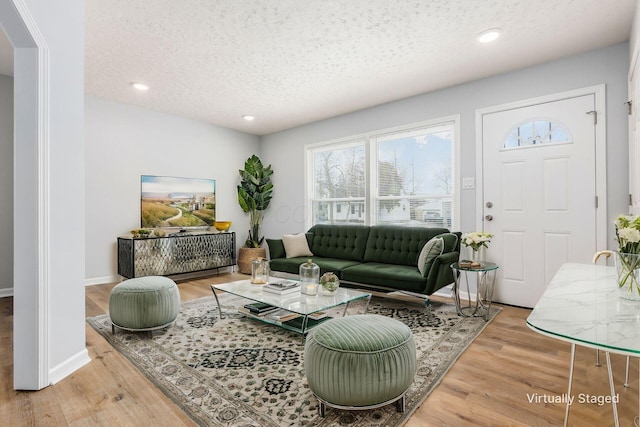 living area featuring a textured ceiling, recessed lighting, wood finished floors, and baseboards