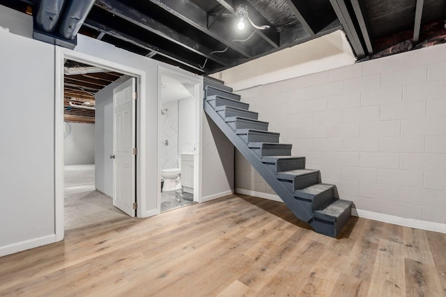 unfinished basement featuring baseboards, stairway, and light wood-style floors