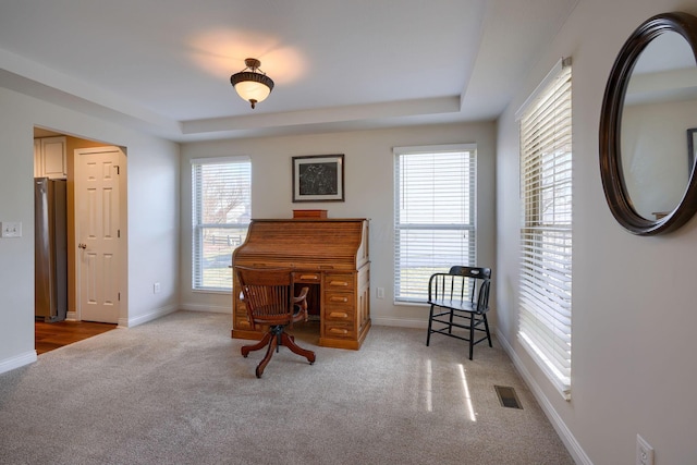 living area with a tray ceiling and light colored carpet