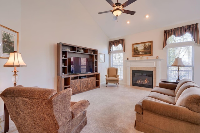 living room with ceiling fan, high vaulted ceiling, a tile fireplace, and light colored carpet