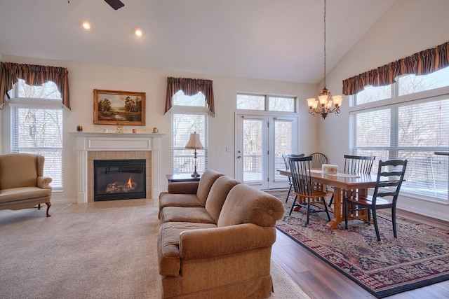 dining room featuring a tiled fireplace, high vaulted ceiling, a notable chandelier, and a wealth of natural light