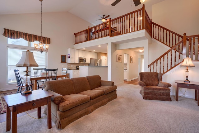 carpeted living room with ceiling fan with notable chandelier and high vaulted ceiling