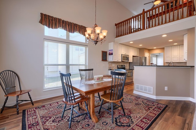 dining room with dark hardwood / wood-style flooring, a notable chandelier, and a towering ceiling