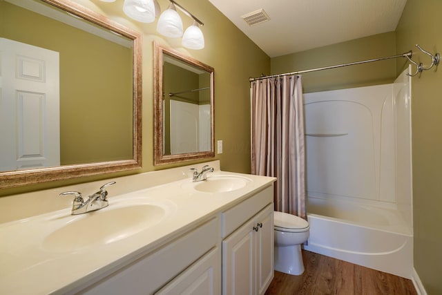 full bathroom featuring hardwood / wood-style flooring, vanity, toilet, and shower / tub combo