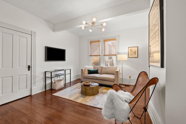 living room featuring an inviting chandelier, dark wood-type flooring, beamed ceiling, and a textured ceiling