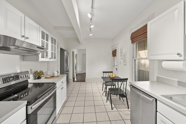 kitchen featuring appliances with stainless steel finishes, white cabinets, light tile patterned floors, rail lighting, and sink