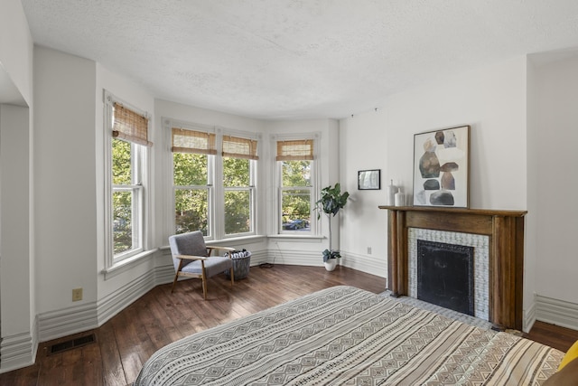 interior space featuring a healthy amount of sunlight, a textured ceiling, dark hardwood / wood-style flooring, and a tiled fireplace