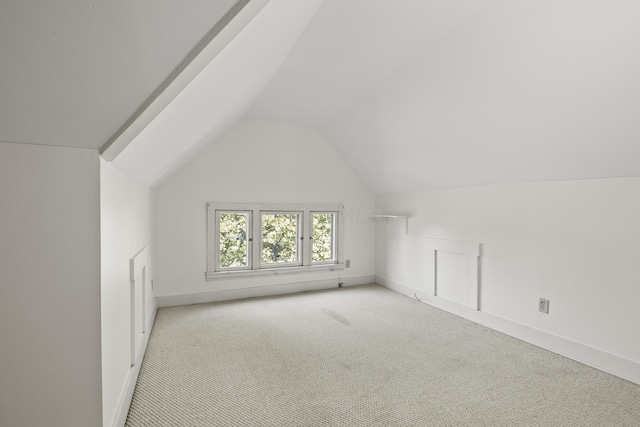 bonus room with vaulted ceiling and light colored carpet