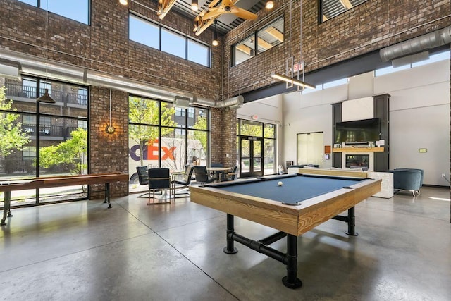 rec room featuring a high ceiling, a wealth of natural light, and finished concrete floors