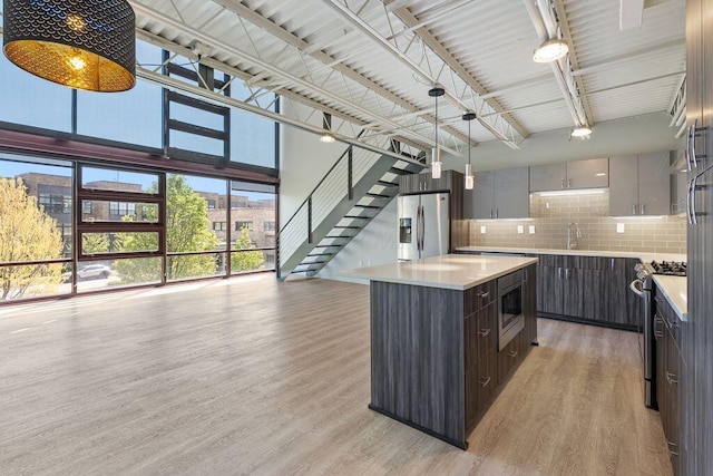 kitchen with light countertops, light wood-style floors, appliances with stainless steel finishes, and tasteful backsplash