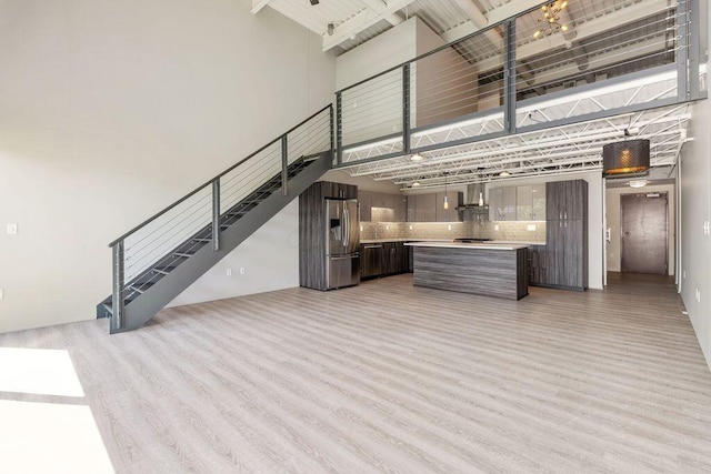 interior space featuring stairs, light wood-style floors, and a towering ceiling